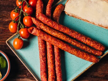 Pfefferbeißer Mediterran angerichtet auf einem Teller mit Tomaten und einem Butterbrot