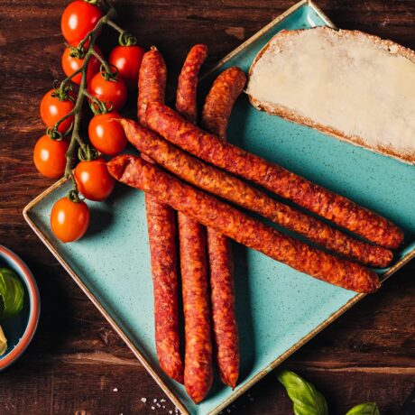 Pfefferbeißer Mediterran angerichtet auf einem Teller mit Tomaten und einem Butterbrot