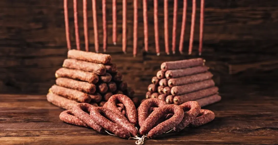 Ahle Wurst gestapelt und gehangen auf einem Tisch präsentiert. Ahle Wurscht kaufen bei Fleischerei Schomberg