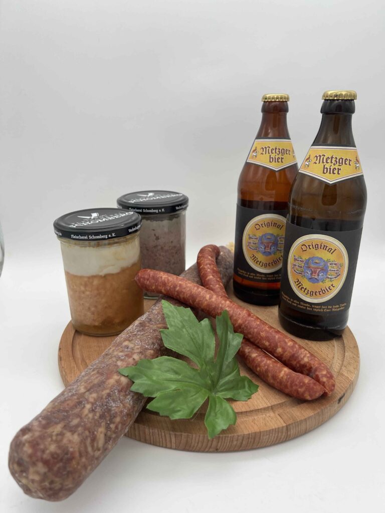 Probierpaket Männer Abend, Ahle wurst, knackige Pfefferbeißer, Leberwurst und 2 Metzgerbiere ordentlich auf einem Holzbrett angerichtet für eine deftige Brotzeit.